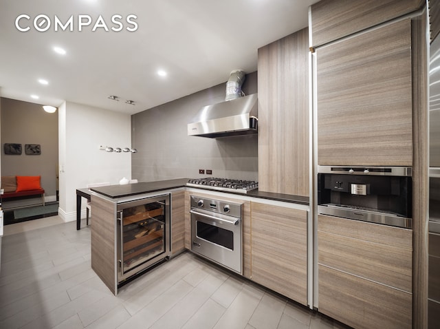 kitchen featuring dark countertops, recessed lighting, wine cooler, appliances with stainless steel finishes, and wall chimney range hood