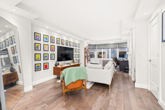 living room featuring baseboards, recessed lighting, wood finished floors, and a raised ceiling