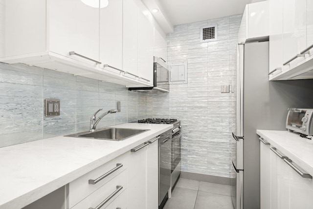 kitchen with visible vents, light tile patterned floors, appliances with stainless steel finishes, white cabinetry, and a sink