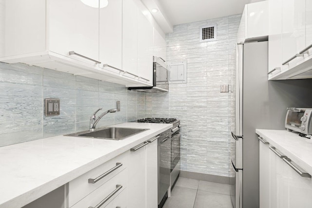 kitchen featuring white cabinets, a sink, light tile patterned floors, tasteful backsplash, and visible vents