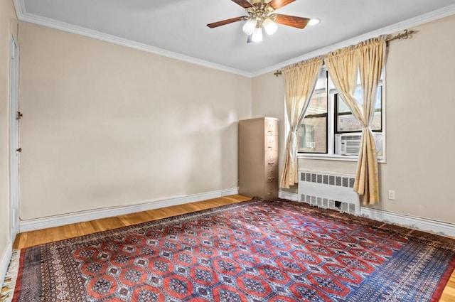 empty room featuring crown molding, radiator, wood finished floors, and baseboards