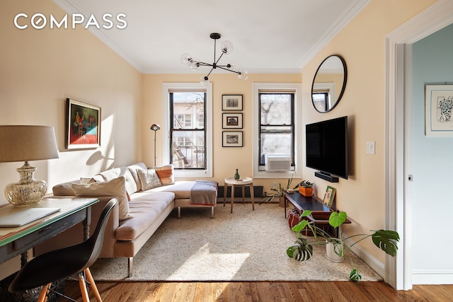 living area with a notable chandelier, wood finished floors, baseboards, and ornamental molding