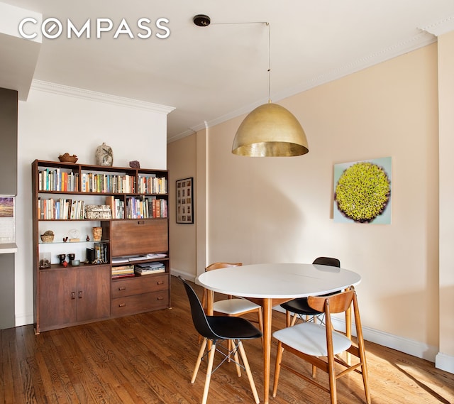 dining space featuring wood finished floors, baseboards, and ornamental molding