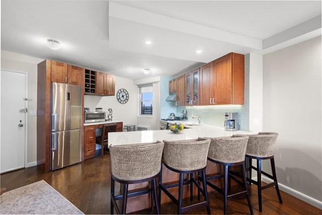 kitchen with stainless steel appliances, brown cabinets, a peninsula, and light countertops