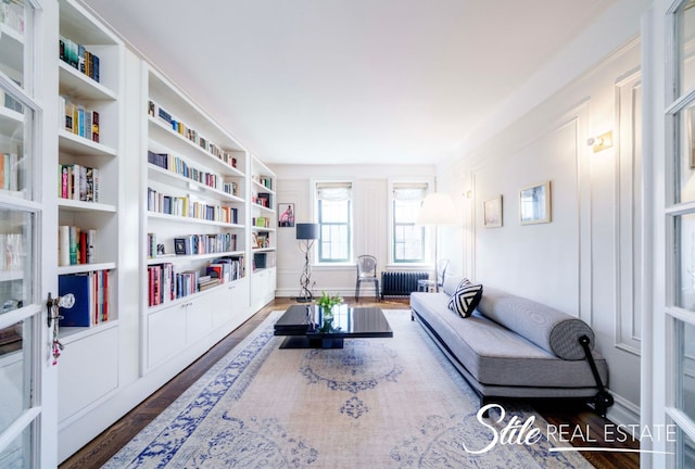 living area with baseboards, radiator, and wood finished floors