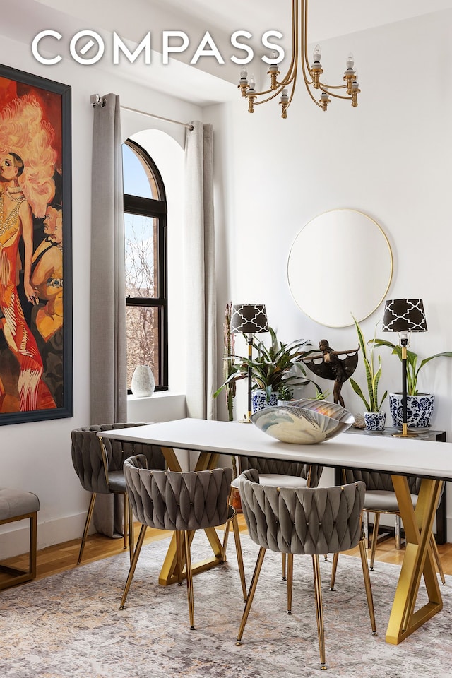 dining area with baseboards, a notable chandelier, and wood finished floors