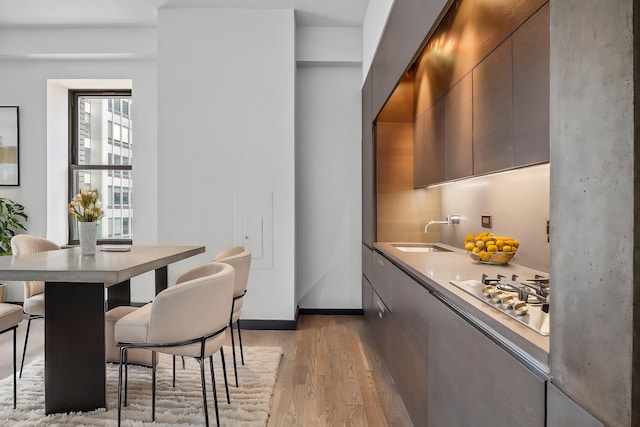 20 Pine St Unit 2907, New York City, NY 10005 - kitchen featuring a sink, modern cabinets, stainless steel gas cooktop, light wood-type flooring, and a breakfast bar area