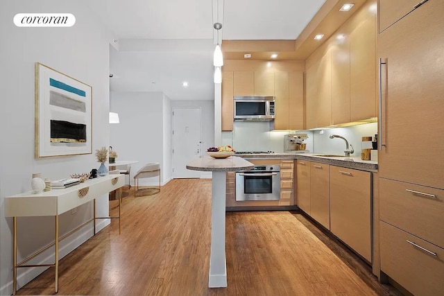 1600 Broadway Unit 16G, New York City, NY 10019 - kitchen with appliances with stainless steel finishes, a sink, wood finished floors, light brown cabinetry, and pendant lighting