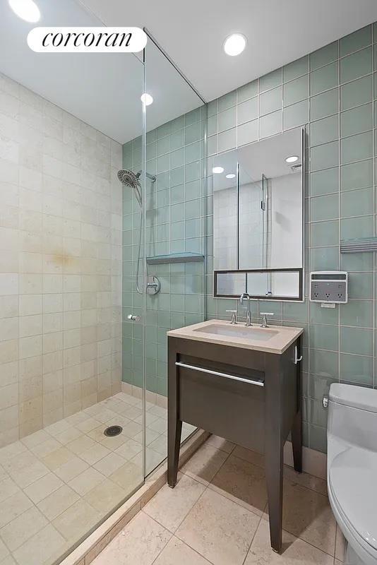 1600 Broadway Unit 16G, New York City, NY 10019 - bathroom with tile walls, toilet, a shower stall, and tile patterned flooring