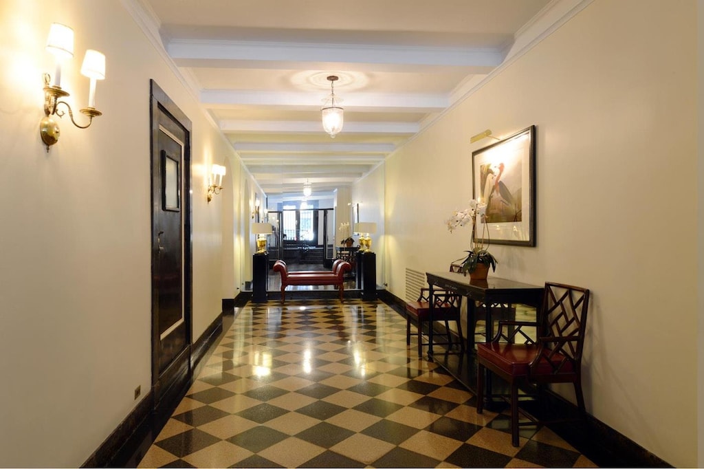 corridor with beam ceiling, crown molding, and baseboards