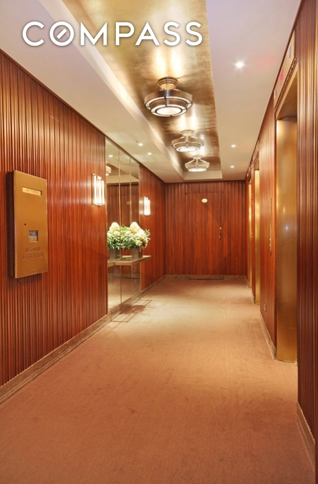 hall with light carpet, recessed lighting, and wood walls