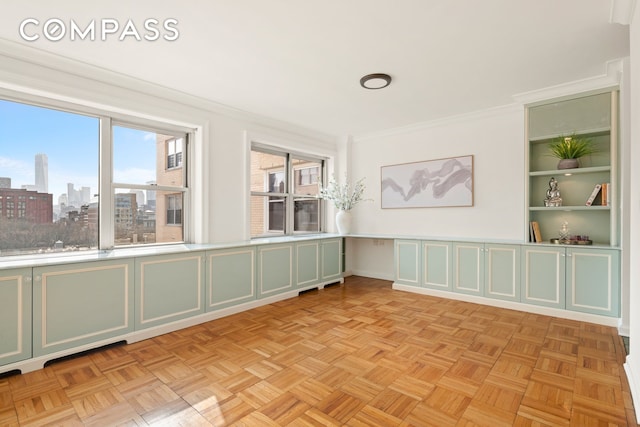 unfurnished room featuring crown molding, a view of city, and built in shelves