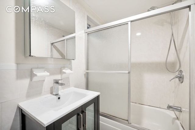 bathroom with vanity, tile walls, backsplash, and shower / bath combination with glass door