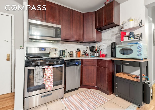 kitchen featuring tasteful backsplash, light countertops, light tile patterned floors, appliances with stainless steel finishes, and open shelves