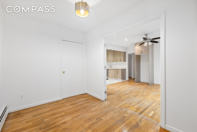 interior space featuring a ceiling fan, baseboards, light wood-type flooring, and baseboard heating