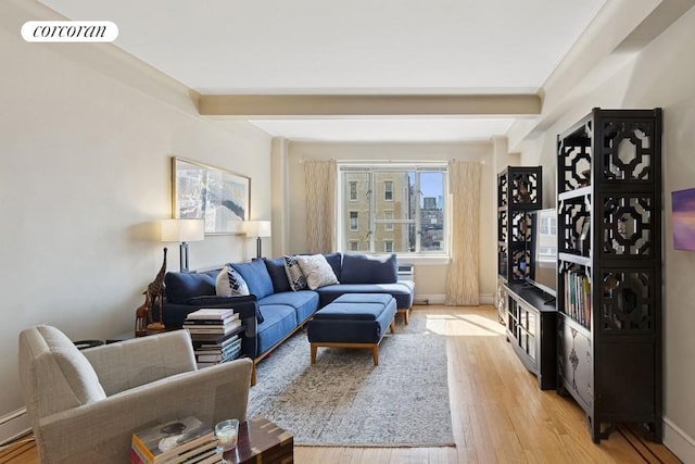 living area with visible vents, a baseboard heating unit, baseboards, beam ceiling, and light wood-style flooring