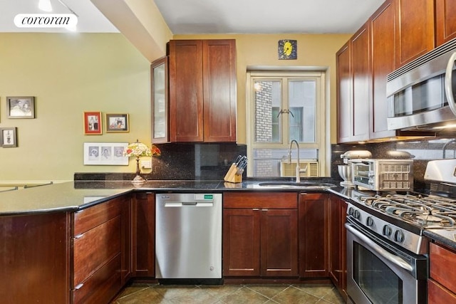 kitchen with visible vents, a peninsula, a sink, stainless steel appliances, and tasteful backsplash