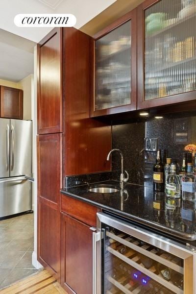 bar with beverage cooler, stainless steel refrigerator, a sink, tasteful backsplash, and wet bar