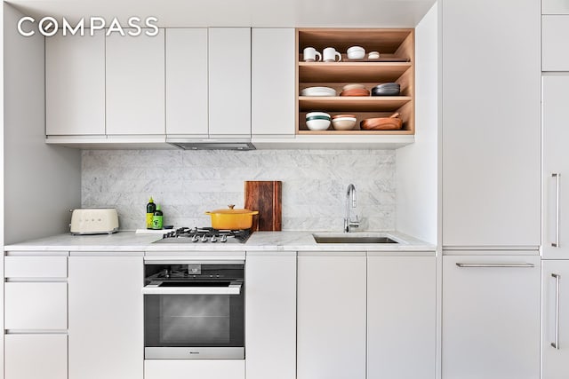 kitchen featuring modern cabinets, a sink, white cabinets, white oven, and stainless steel gas cooktop