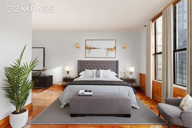 bedroom with ornamental molding and wood finished floors