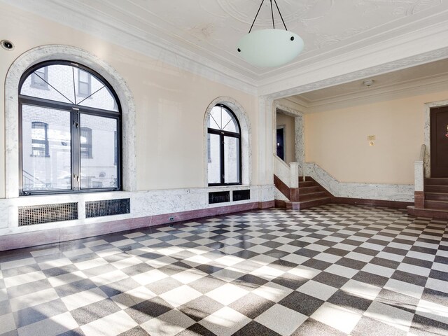entryway featuring tile patterned floors, a tray ceiling, and ornamental molding