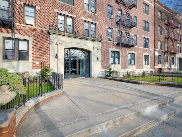 property entrance featuring fence, cooling unit, french doors, and brick siding