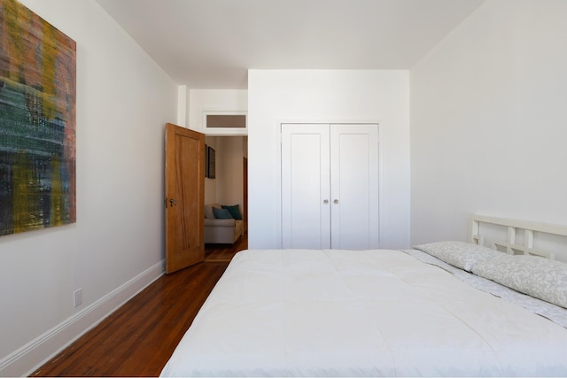 bedroom with dark wood-type flooring, baseboards, and a closet