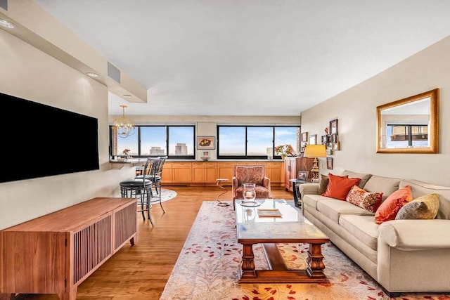 living room featuring light wood-style floors, visible vents, and a chandelier