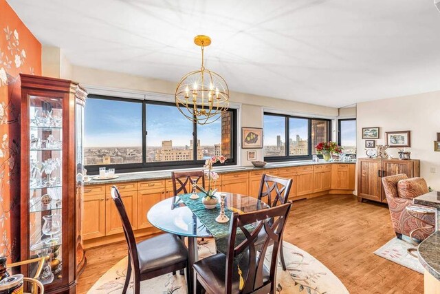 dining area with a city view, an inviting chandelier, and light wood-style floors