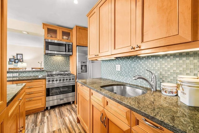 1725 York Ave Unit 26E, New York City, NY 10128 - kitchen featuring stainless steel appliances, a sink, backsplash, glass insert cabinets, and dark stone counters