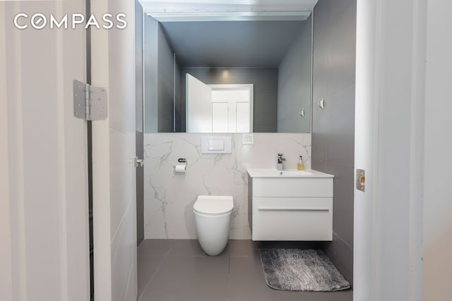 bathroom with tile patterned floors, toilet, vanity, and tile walls