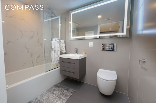 full bathroom featuring visible vents, toilet, shower / washtub combination, tile walls, and vanity