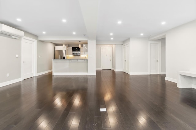 unfurnished living room featuring dark wood-style floors, recessed lighting, a wall mounted air conditioner, and baseboards