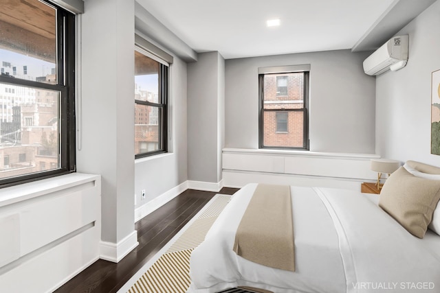 bedroom with an AC wall unit, baseboards, and dark wood-style flooring