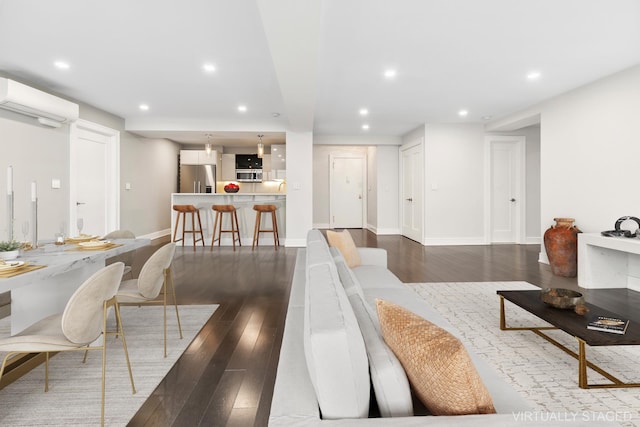 living room featuring recessed lighting, dark wood-style flooring, a wall mounted air conditioner, and baseboards