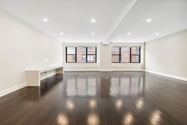 unfurnished living room with a wealth of natural light, baseboards, and dark wood-type flooring