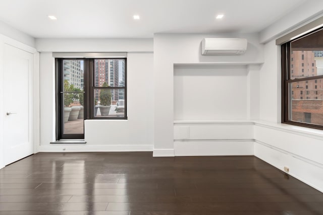 empty room with a wall mounted air conditioner, baseboards, dark wood-type flooring, and recessed lighting