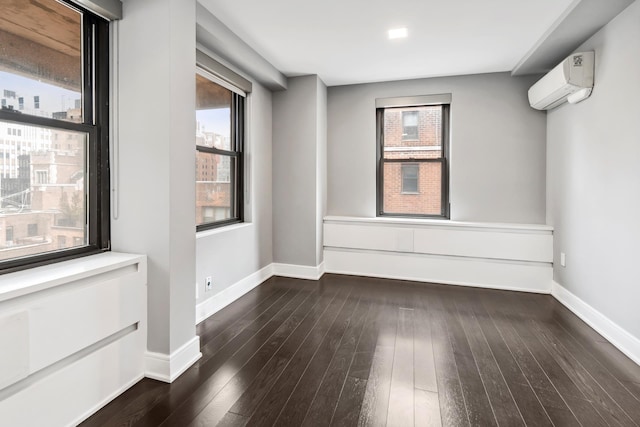 unfurnished room featuring an AC wall unit, baseboards, and hardwood / wood-style flooring