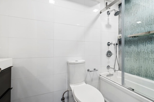 bathroom featuring enclosed tub / shower combo, toilet, tile walls, and vanity