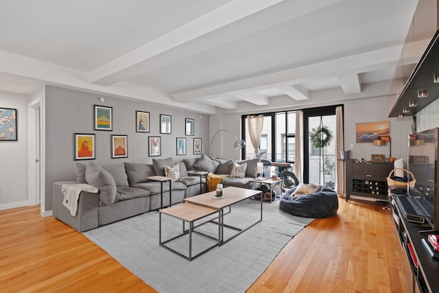 living room featuring beam ceiling, baseboards, and light wood-type flooring