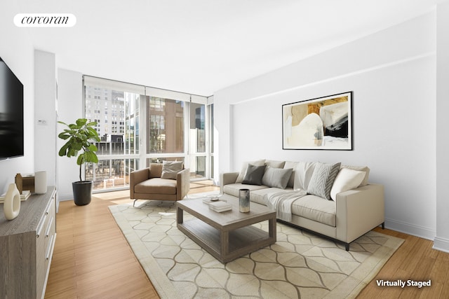 living room featuring baseboards, visible vents, light wood finished floors, and expansive windows