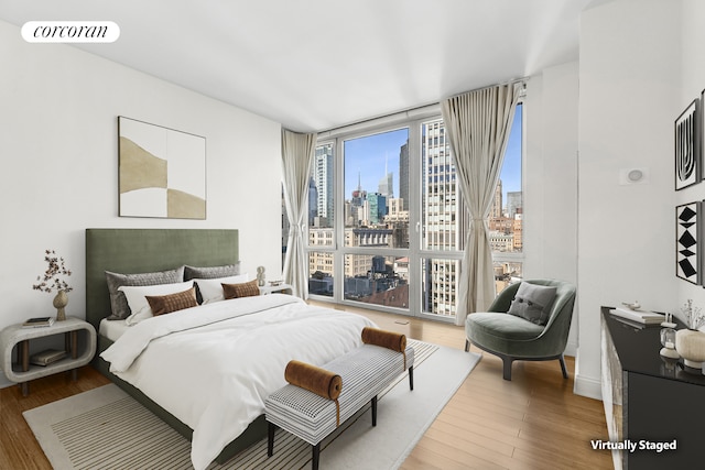 bedroom featuring visible vents, a city view, wood finished floors, and floor to ceiling windows