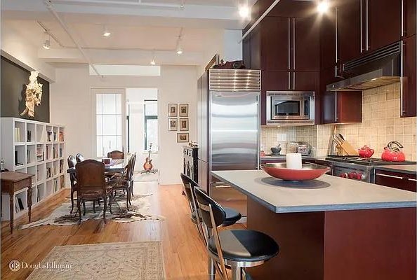 kitchen featuring backsplash, under cabinet range hood, built in appliances, a breakfast bar, and light wood-type flooring