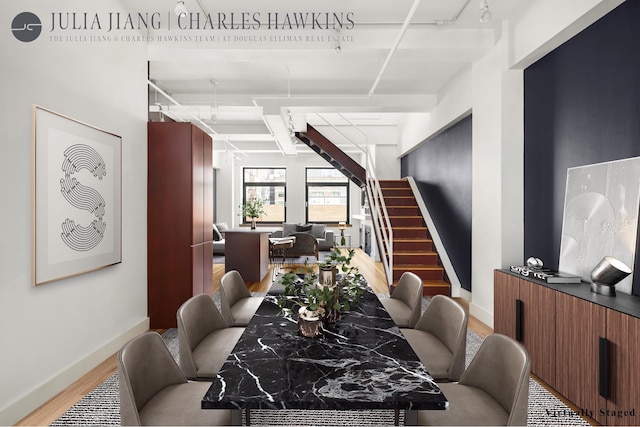 dining space featuring light wood-type flooring, stairs, and baseboards