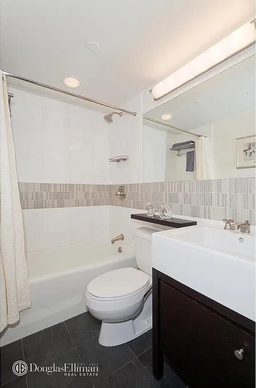 bathroom featuring shower / bathtub combination with curtain, toilet, tile walls, tile patterned flooring, and vanity