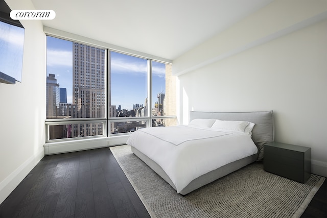 bedroom featuring a city view, baseboards, and hardwood / wood-style flooring