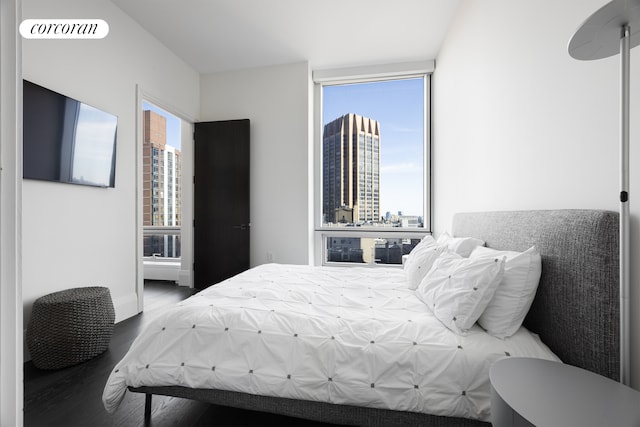 bedroom featuring a city view, wood finished floors, and visible vents