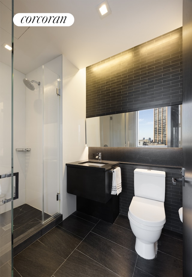 full bath featuring tile patterned flooring, a shower stall, tile walls, toilet, and vanity