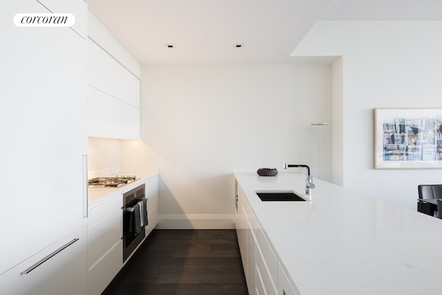 kitchen with dark wood-style flooring, a sink, stainless steel appliances, white cabinetry, and modern cabinets