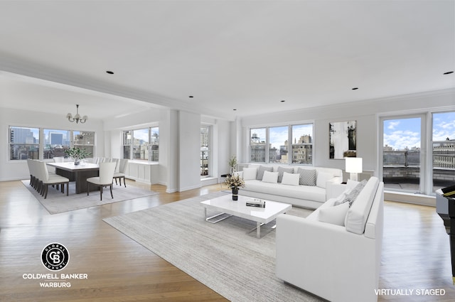 living room with an inviting chandelier, a view of city, light wood-type flooring, and ornamental molding